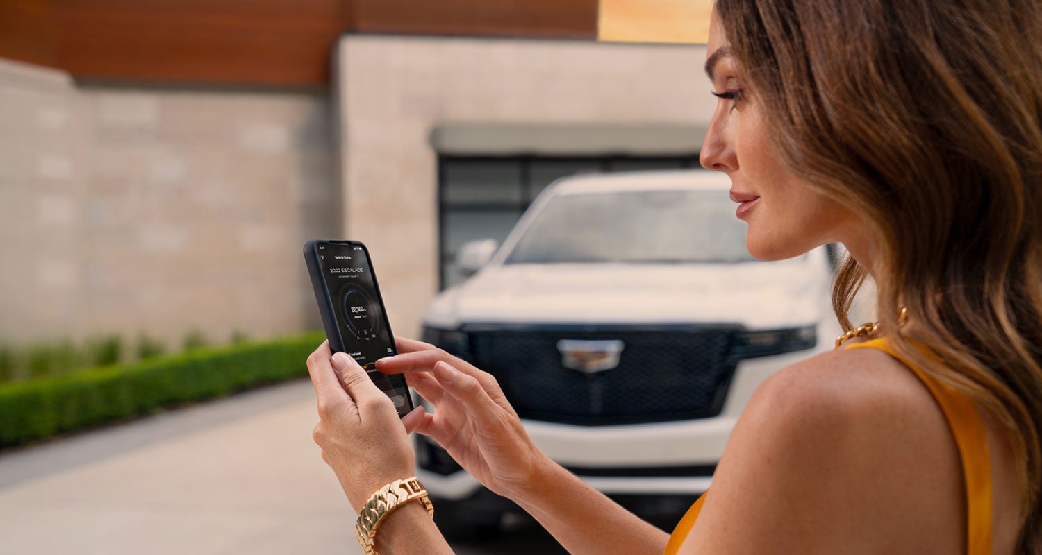 lady checking her mobile with a Cadillac vehicle background | Joe Cooper Cadillac of Shawnee in Shawnee OK