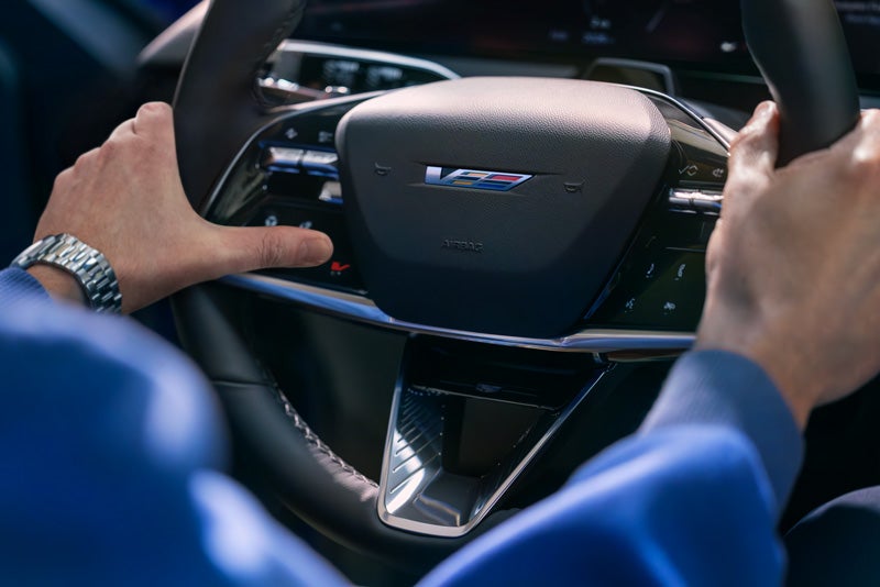 Close-up of a Man About to Press the V-Button on the 2026 OPTIQ-V Steering Wheel | Joe Cooper Cadillac of Shawnee in Shawnee OK